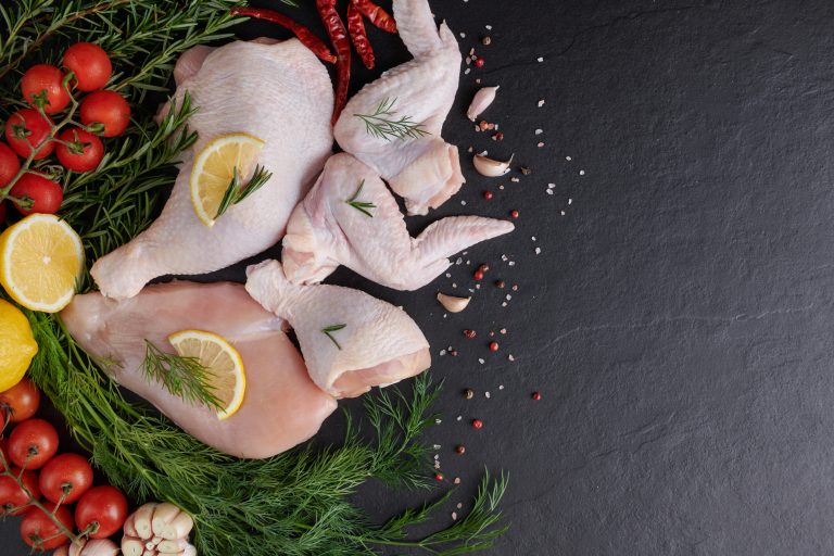 raw chicken fillet with garlic, pepper and rosemary on wooden on chopping board. fresh fillet. fresh chicken meat, chicken fillet with spices at black stone table. top view with copy space.