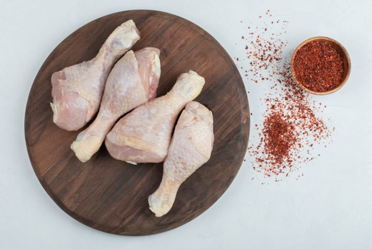 raw-fresh-chicken-legs-with-red-hot-chili-peppers-white-background